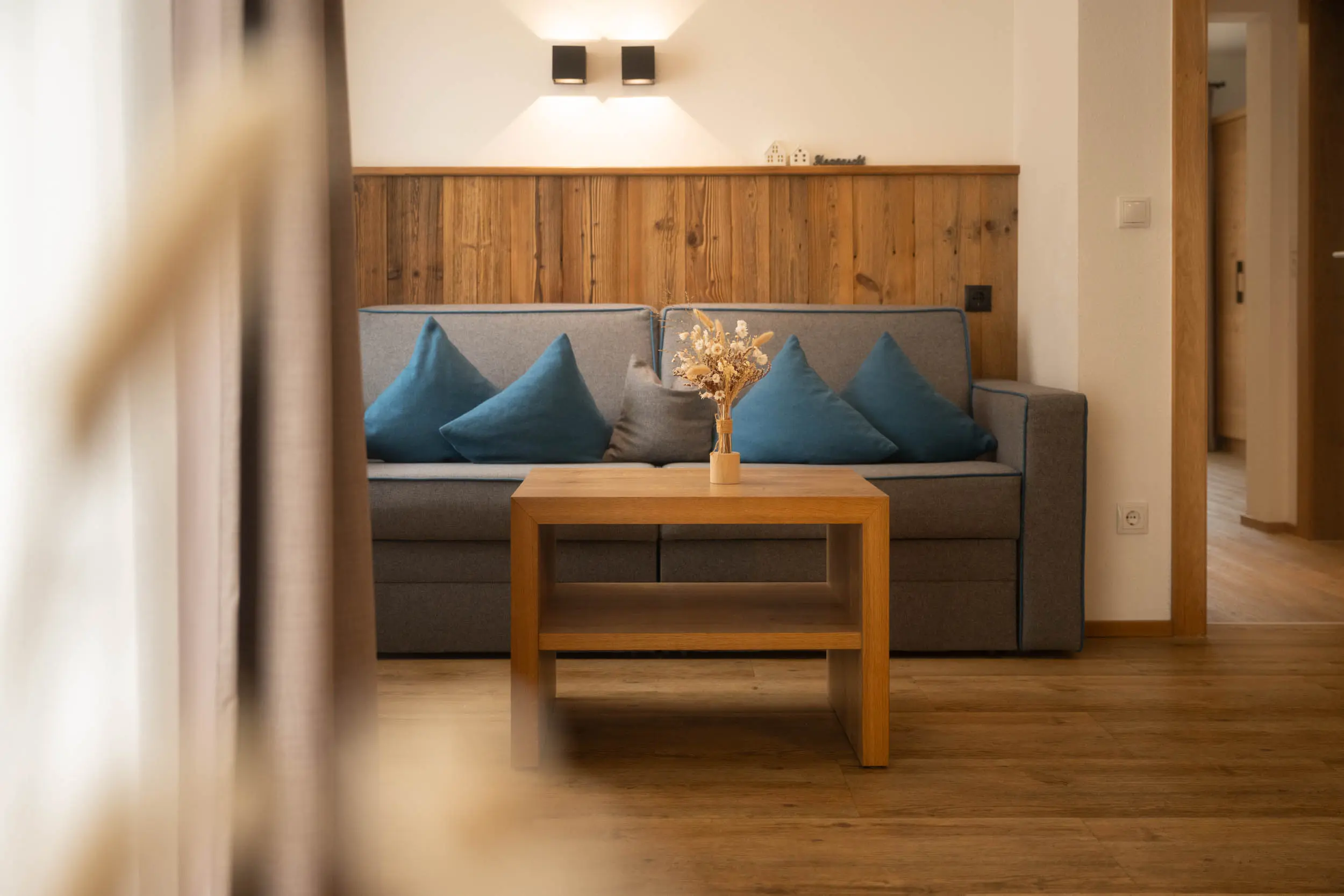 Essecke mit blauen Kissen und Holztisch im stoanmandl Appartement